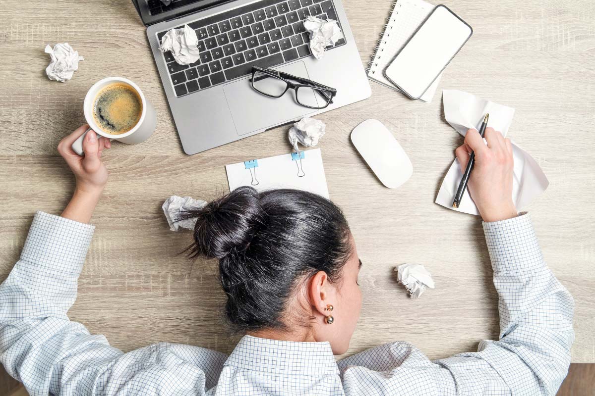 overwhelmed IT professional lays head on her desk, struggling to map out clear IT asset management plan
