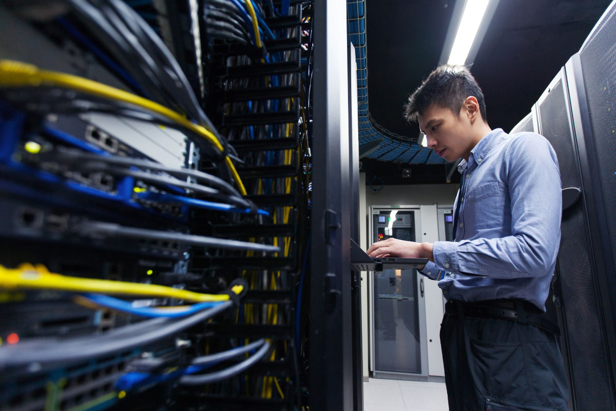 IT technician configuring network equipment after hours in a server room during rollout deployment